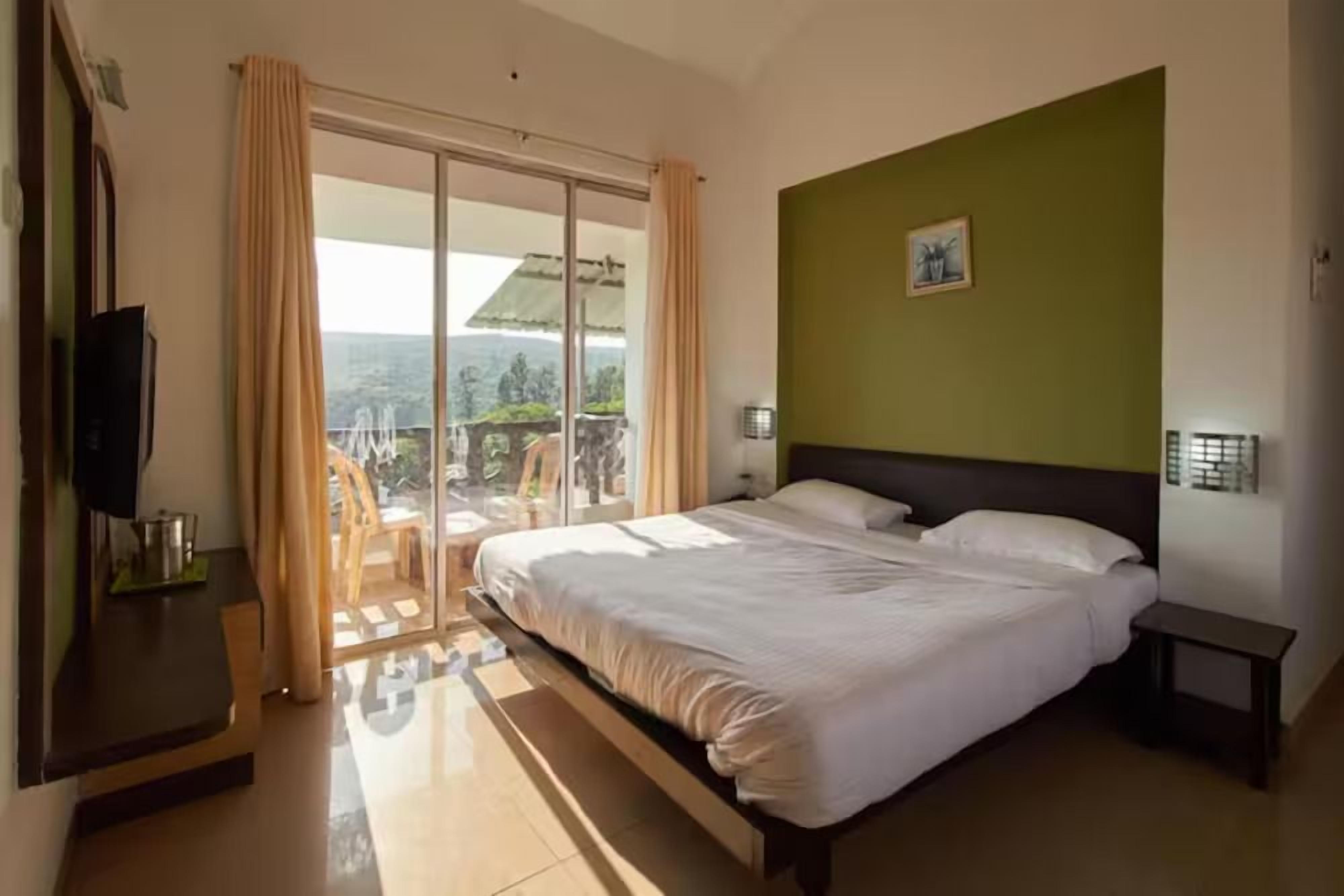 Una habitación de hotel con una cama, televisión, escritorio y vistas al exterior.