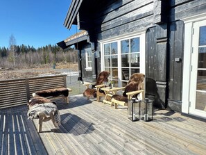 A wooden deck with outdoor seating and a glass door leading to a building.