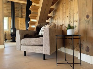 A cozy living room with a sofa, a small side table with a plant, and a fireplace. - Familycabin at a lake (Ringsaker)
