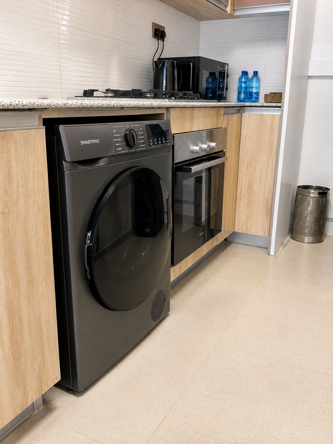 Eine moderne Küche mit einer Frontlader-Waschmaschine, einem eingebauten Backofen und einer Mikrowelle.