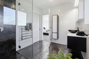 A modern bathroom with a glass shower enclosure, a black sink, and a large mirror. - Summer Breeze Staycation (Tasman City)