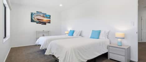 A hotel room with two beds, a nightstand with a lamp, a painting on the wall, and a carpeted floor.