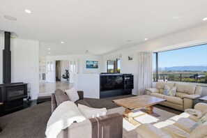 A spacious living room with a fireplace, a sofa set, a coffee table, and a large TV. - Summer Breeze Staycation (Tasman City)