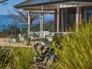 A modern house with a covered patio, outdoor seating, and a view of mountains. - Summer Breeze Staycation (Tasman City)