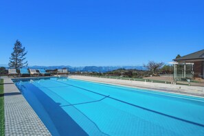 A swimming pool with lounge chairs and a view of the mountains. - Summer Breeze Staycation (Tasman City)