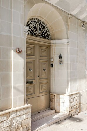 A double wooden door with a decorative fan above it, set within a stone wall. - Spirit of Malta Townhouse with late checkout (Sliema)