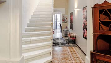 Eine Treppe führt zu einer Zwischenebene mit einem gemusterten Boden, einem Holzschrank und einer Wand mit gerahmten Kunstwerken.