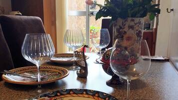 A dining table set with plates, cutlery, and wine glasses, with a vase of flowers in the background.