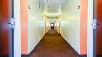 Un long couloir étroit, avec des portes de part et d’autre, qui mène à un point central.