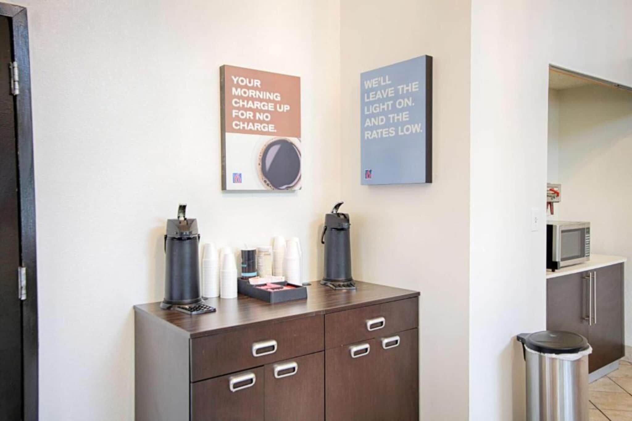 A hotel reception area with a coffee station, a microwave, and a trash bin.