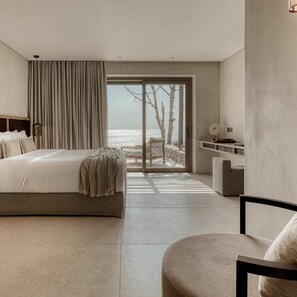 Un dormitorio moderno con una cama grande, un área de descanso y vista al mar.