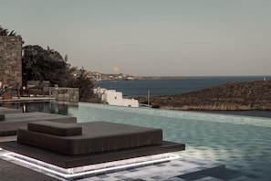 Una piscina infinita con vistas al mar y al atardecer.