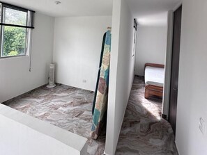 Ein Zimmer mit Marmorboden, einem Bett mit Holzrahmen, einem Fenster mit Jalousien und einer Heizung.