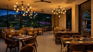 Un restaurante con mesas y sillas dispuestas para comer, amplias ventanas que ofrecen vistas al exterior y un ventilador de techo.