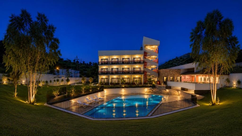 Ein modernes Hotel mit Schwimmbad, mehreren Balkonen und einem angelegten Garten.