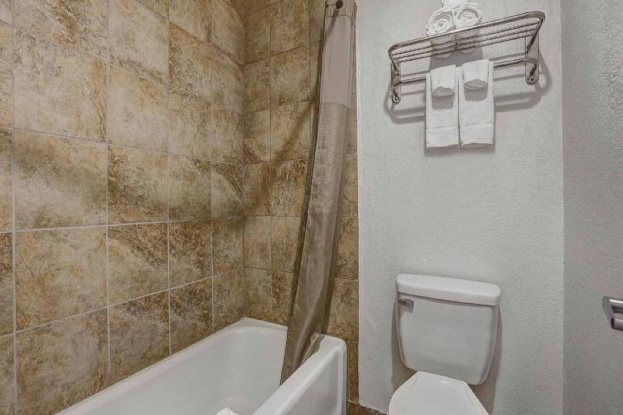 Une salle de bain équipée d’une baignoire, d’un rideau de douche, de toilettes et d’un porte-serviettes avec des serviettes.
