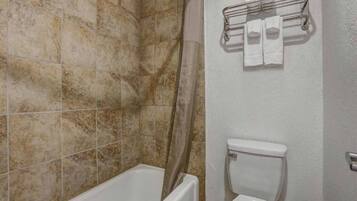 Une salle de bain équipée d’une baignoire, d’un rideau de douche, de toilettes et d’un porte-serviettes avec des serviettes.