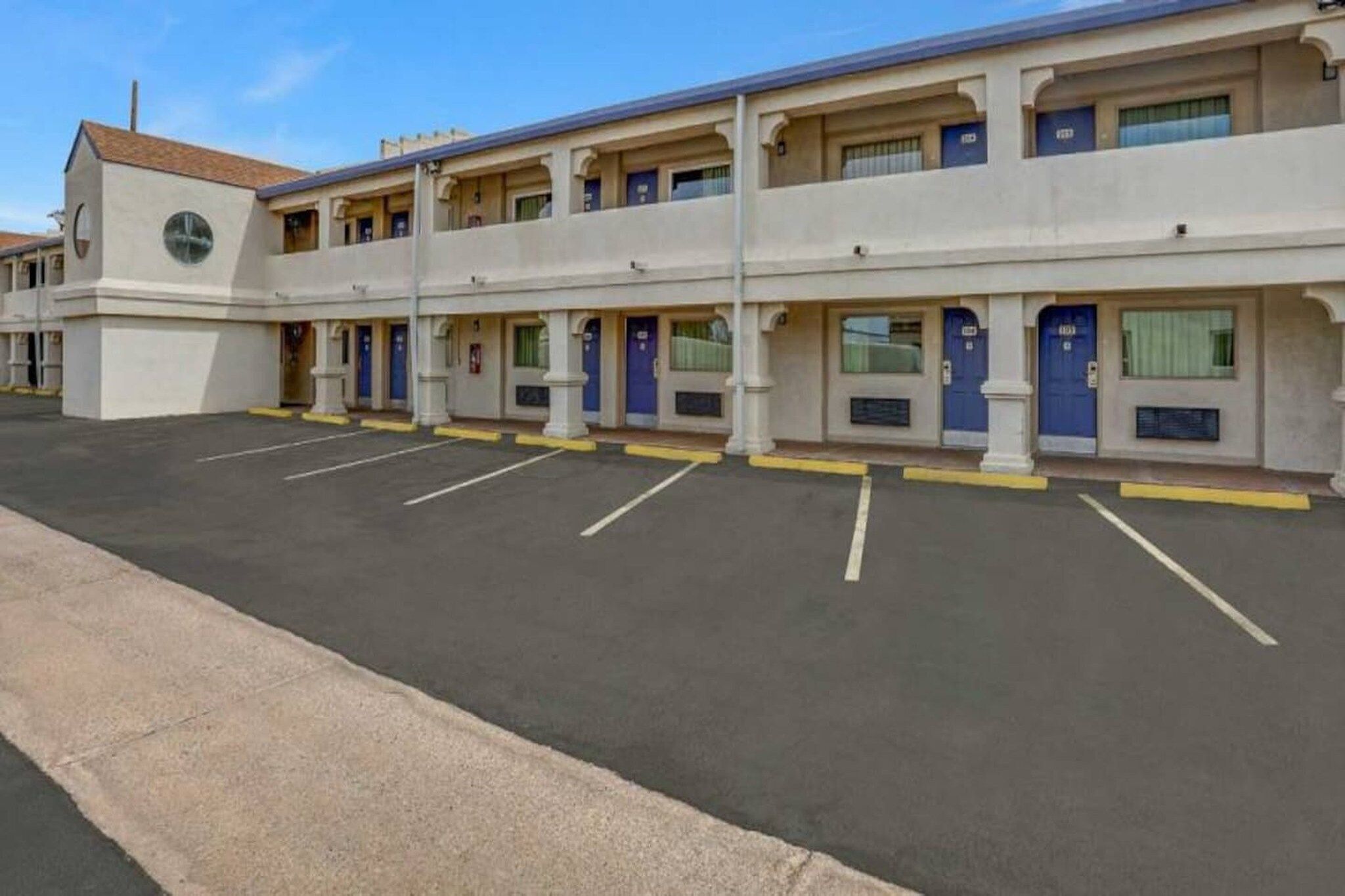 Et motel med flere etager og en række værelser, hver med dør og vindue.