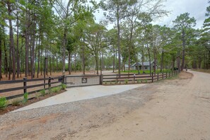 A gravel driveway leading to a fenced property with a house and a gate labeled 'PO Box Squid.' - Piney Woods Retreat w/ Sauna, Fire Pit & Games (Willis)