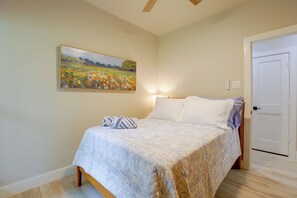 A bedroom with a bed, a painting, and a door. - Piney Woods Retreat w/ Sauna, Fire Pit & Games (Willis)