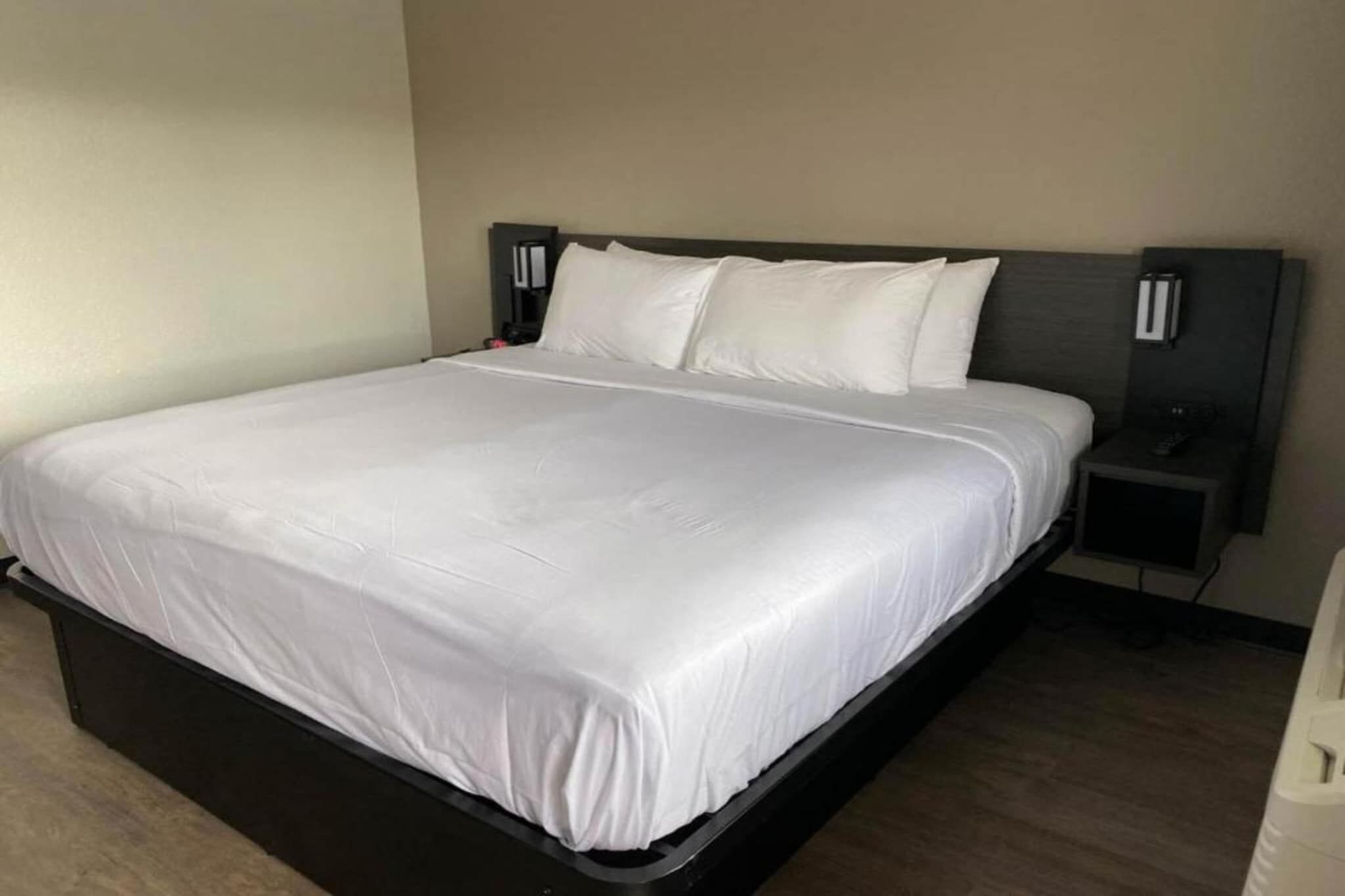 Une chambre d’hôtel standard, équipée d’un lit simple, d’une table de chevet et d’une petite table.