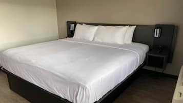 Une chambre d’hôtel standard, équipée d’un lit simple, d’une table de chevet et d’une petite table.