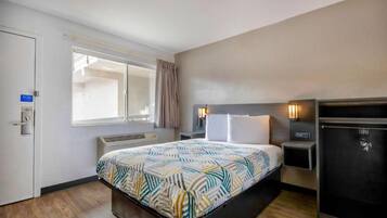 Habitación de hotel con cama, mesitas de noche, armario, ventana y puerta.