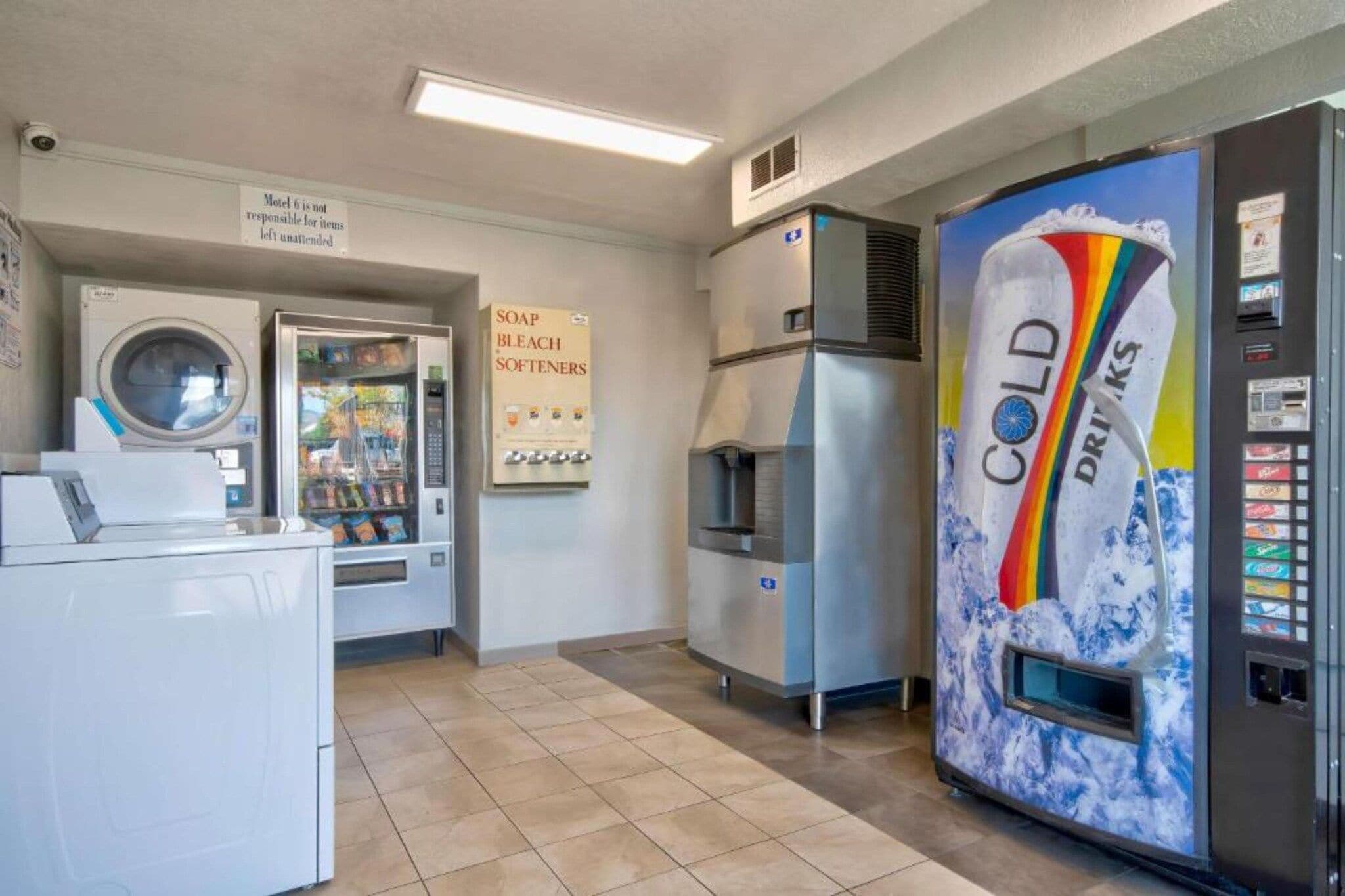 Eine Wäscherei mit Waschmaschine, Getränkeautomaten und Kühlschrank mit Regenbogen-Motiv.