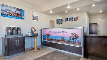 A reception area with a digital display, a coffee station, and a counter.