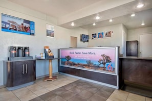 A reception area with a digital display, a coffee station, and a counter. - 1 King Bed | Micfridge (Albuquerque NM)