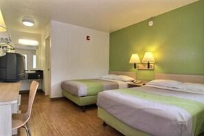 Ein Hotelzimmer mit zwei Betten, einem Schreibtisch, einem Stuhl und einem Fernseher.