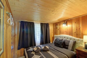 A wooden-paneled room with a bed, curtains, and a nightstand. - Sibley Shores Waterfront Cabin w/ Dock & 28 Acres (Pequot Lakes)
