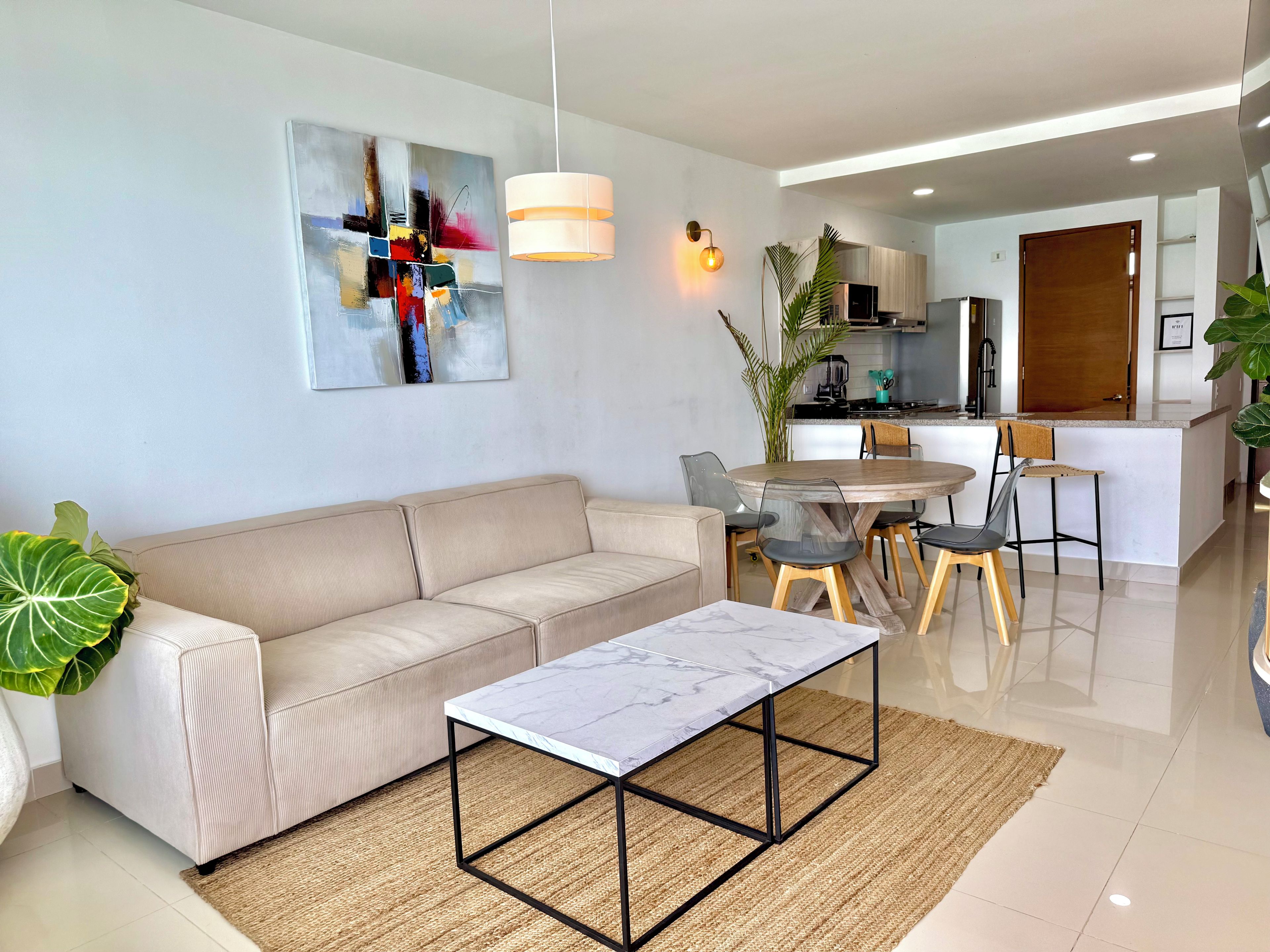 A modern living room with a sofa, a coffee table, and a dining area with chairs.