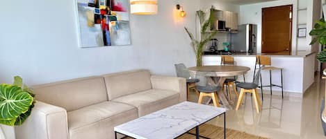 A modern living room with a sofa, a coffee table, and a dining area with chairs.