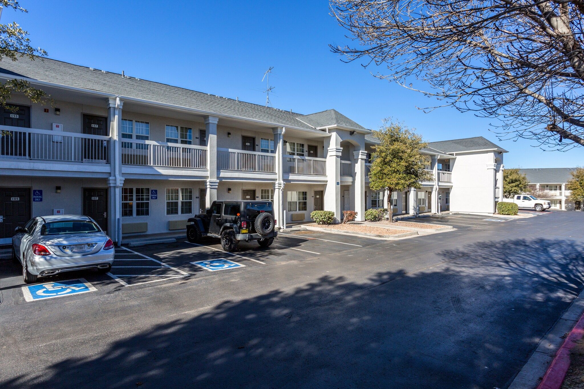 A multi-story motel with parking spaces, including a handicapped accessible spot.