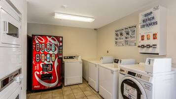 A laundry facility with a vending machine, dryers, washers, and detergent dispensers.