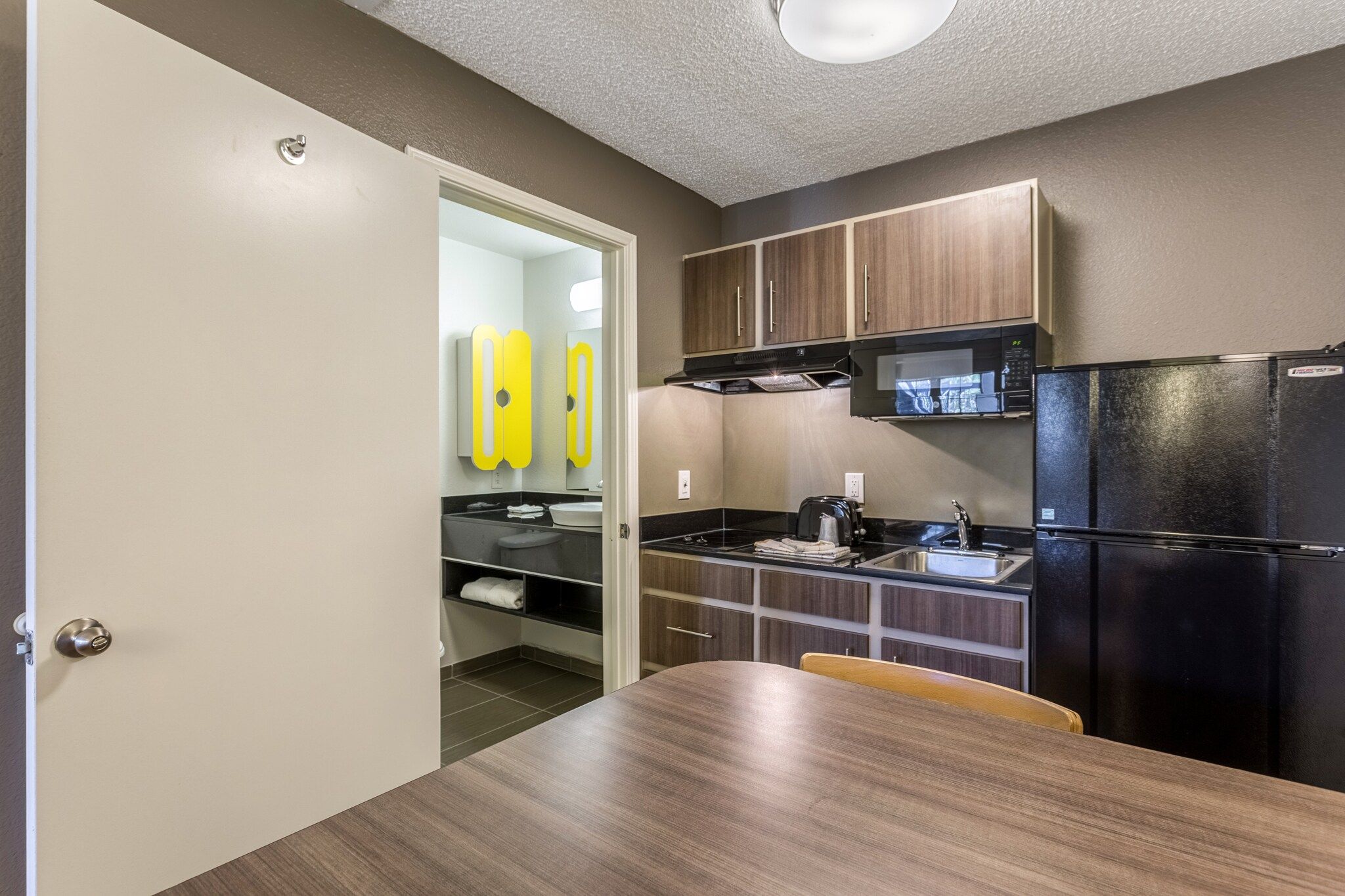A compact kitchen with a refrigerator, microwave, and a sink.