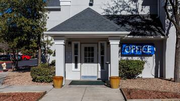 A building with a sign indicating an office. There are two large planters in front of the entrance.
