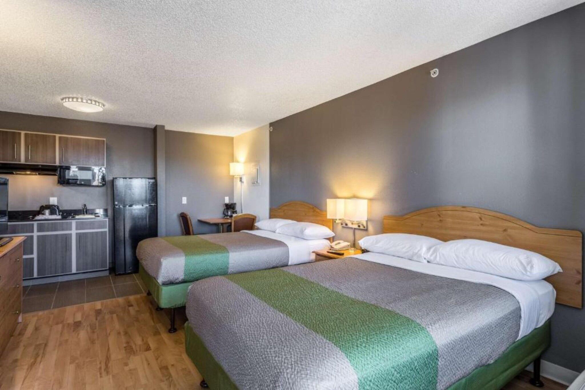 A hotel room with two beds, a kitchenette, and a dining area.