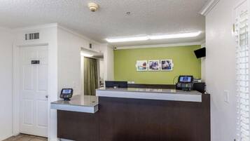 A reception desk with a digital screen, a telephone, and a cash register.