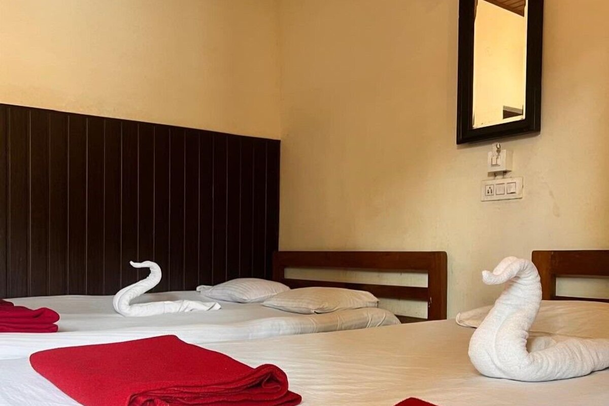 A hotel room with two beds, each with a white swan-shaped towel and a red towel.