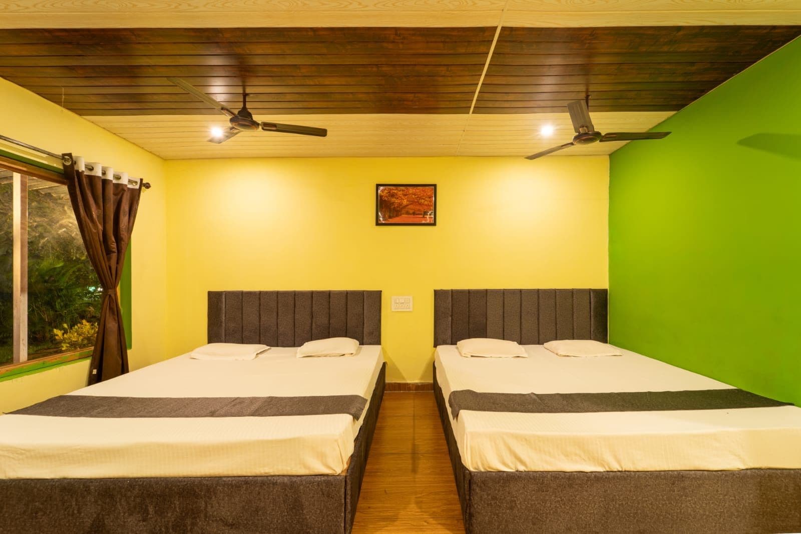 Habitación con dos camas, techo de madera y pared verde.