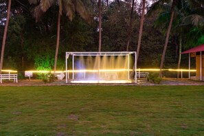 A covered outdoor area with a water feature, surrounded by a fence and palm trees.