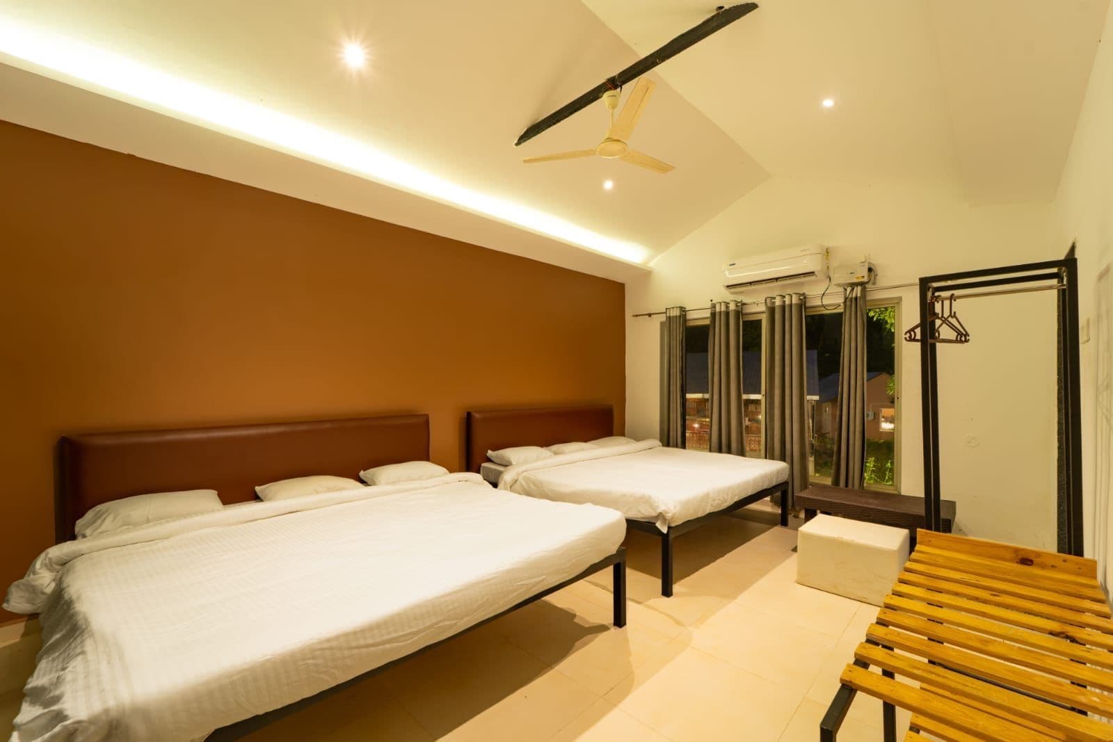 Habitación de hotel con dos camas, ventilador de techo, aire acondicionado y vista al exterior.