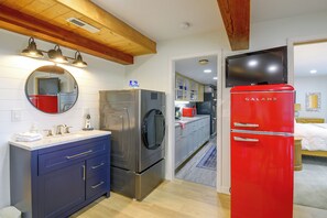 A compact kitchen with modern appliances, a built-in oven, and a red refrigerator. - Puget Sound Views & Patio: Point No Point Apt (Hansville)
