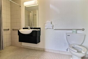 Et badeværelse med hvid vask, sort kommode, et spejl, et håndklædestativ og et toilet.