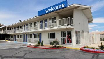 Un hotel con un letrero de 'welcome', un estacionamiento y un edificio con varias puertas y ventanas.