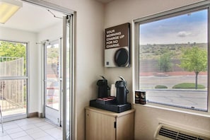 A room with a sliding glass door leading to a balcony, a coffee machine, and a wall-mounted speaker. - 1 King Bed | Non-Smoking (Albuquerque)