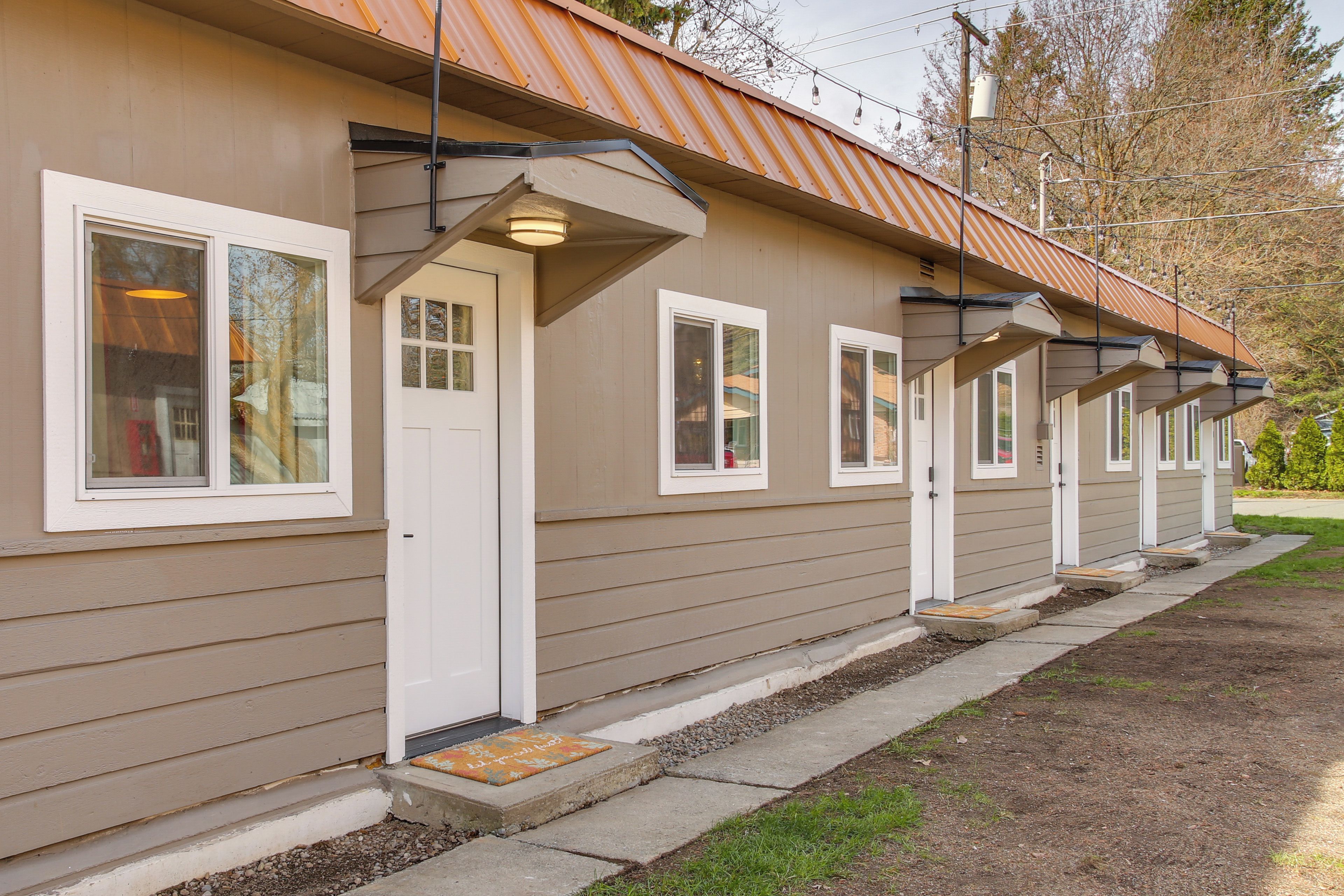 A row of single-story buildings with a uniform exterior design, featuring a series of windows and doors aligned along the facade.