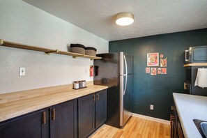 Eine Küche mit dunklen Schränken, einem Edelstahl-Kühlschrank, Holz Arbeitsplatten und einer Mikrowelle.